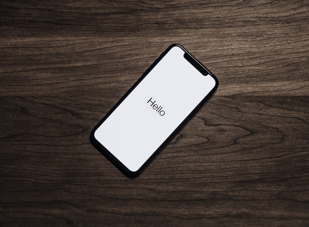 about-02 A smartphone displaying 'Hello' on a wooden surface, showcasing modern technology.